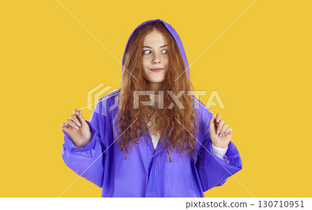Funny redhead curly teenage girl uses waterproof raincoat for walk in autumn rainy weather. 130710951
