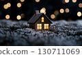 Cozy snowy night scene with illuminated miniature house and warm lights 130711069