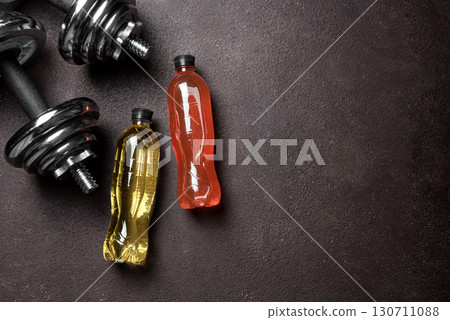 Isotonic sport drink with dumbbells on dark background 130711088