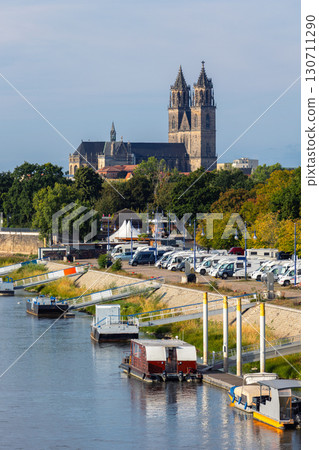 Magdeburg Elbe river embankment panoramic scenic view rv camper van motorhome parking camp church cathedral old cityscape dramatic blue sky. Riverside green city skyline historic tower urban building Magdeburg Elbe river embankment panoramic scenic view rv camper van motorhome parking camp church cathedral old cityscape dramatic blue sky. Riverside green city skyline historic tower urban building 130711290