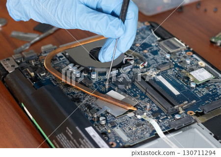 A technician is repairing the motherboard of a laptop computer. 130711294