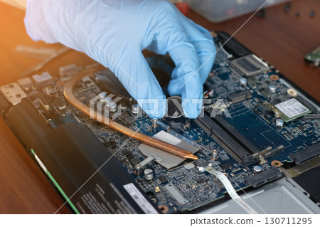 A technician is installing the battery, BIOS and repairing the motherboard of a laptop computer. 130711295