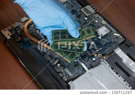 A technician is holding RAM to check and repair the computer motherboard. 130711297