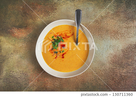 pumpkin cream soup, in a white bowl on a textured background, top view, homemade, no people, rustic style, 130711360