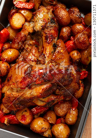 Pork knuckle, baked with vegetables, new potatoes , on a baking sheet, homemade, no people, 130711371