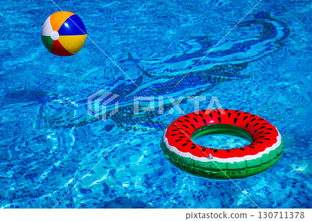 Colorful beach ball and watermelon circle, floating in the pool water, on a sunny summer day, no people Colorful beach ball and watermelon circle, floating in the pool water, on a sunny summer day, no people 130711378