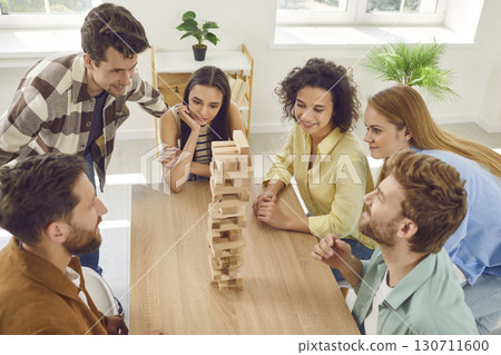 Group of a happy friends playing together with wooden building blocks at home. 130711600