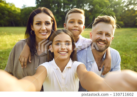 Happy mom, dad and children having fun and taking family selfie in green summer park Happy mom, dad and children having fun and taking family selfie in green summer park 130711602