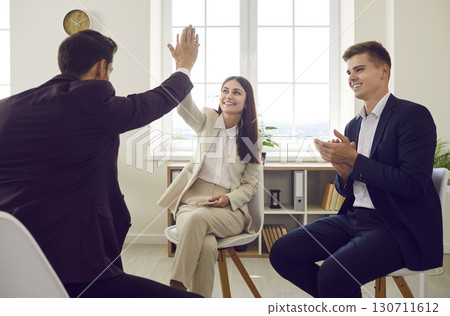 Business people sitting in office and making deal. Man giving high five to woman finishing meeting 130711612