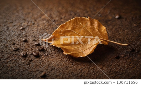 Close-up of an autumn leaf on coffee grounds with scattered coffee beans. Concept: warm still life, texture, and seasonal mood. Close-up of an autumn leaf on coffee grounds with scattered coffee beans. Concept: warm still life, texture, and seasonal mood. 130711656