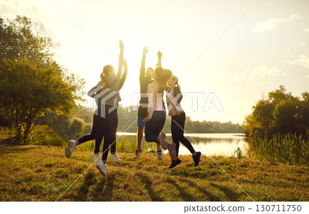 A group of athletes jumping joyfully in nature at sunset 130711750