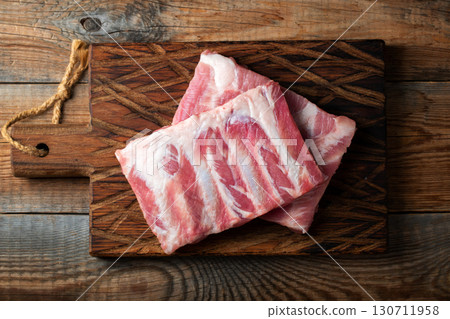 Raw pork ribs with spices, salt and rosemary on dark wooden background Raw pork ribs with spices, salt and rosemary on dark wooden background 130711958