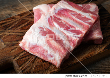 Raw pork ribs with spices, salt and rosemary on dark wooden background 130711959