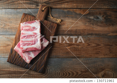 Raw pork ribs with spices, salt and rosemary on dark wooden background 130711961
