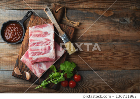 Raw pork ribs with spices, salt and rosemary on dark wooden background 130711962