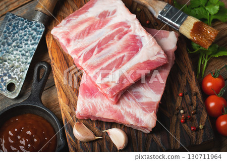 Raw pork ribs with spices, salt and rosemary on dark wooden background 130711964
