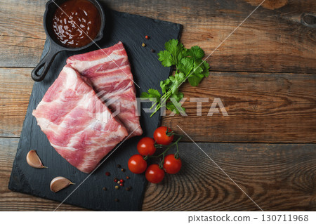 Raw pork ribs with spices, salt and rosemary on dark wooden background 130711968