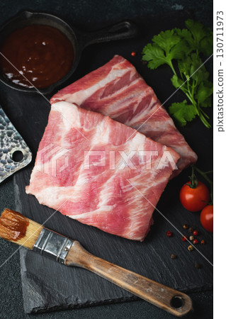 Raw meat. Raw pork ribs from the back with meat on a black background. background image Raw meat. Raw pork ribs from the back with meat on a black background. background image 130711973