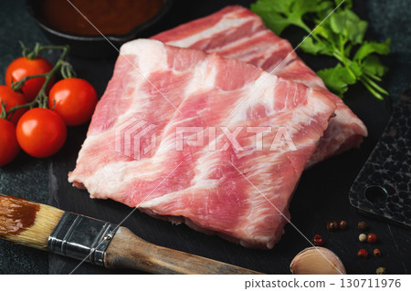 Raw meat. Raw pork ribs from the back with meat on a black background. background image Raw meat. Raw pork ribs from the back with meat on a black background. background image 130711976