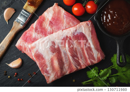 Raw meat. Raw pork ribs from the back with meat on a black background. background image 130711980