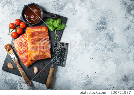 Ready for BBQ raw pork spare ribs with barbecue sauce. Black background. Top view 130711987