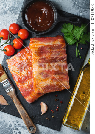 Ready for BBQ raw pork spare ribs with barbecue sauce. Black background. Top view 130711988