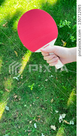 Young female hand holding table tennis racket in garden Young female hand holding table tennis racket in garden 130712065