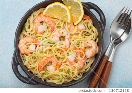 Delicious seafood pasta spaghetti with shrimps dish garnished with lemon and parsley top view on light blue background Delicious seafood pasta spaghetti with shrimps dish garnished with lemon and parsley top view on light blue background 130712128