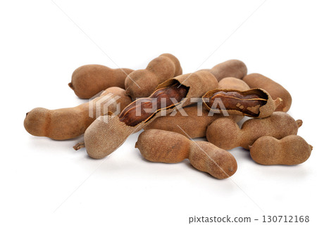 A pile of tamarind pods, some cracked open to reveal the pulp, on a white background. Represents exotic fruit 130712168
