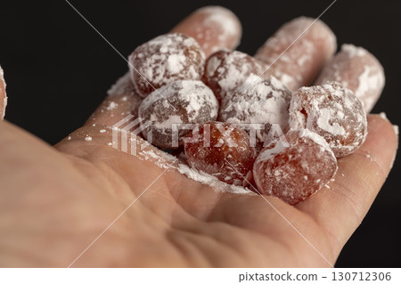 dried kumquat and powdered sugar in the hand, sweet dried orange kumquat fruits in white powdered sugar dried kumquat and powdered sugar in the hand, sweet dried orange kumquat fruits in white powdered sugar 130712306