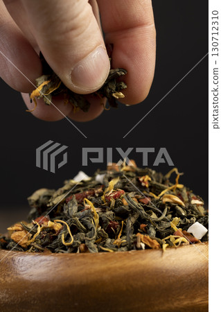 large-leaved green tea poured into a wooden cup with the addition of fruits , dry high-quality expensive tea in a wooden bowl 130712310