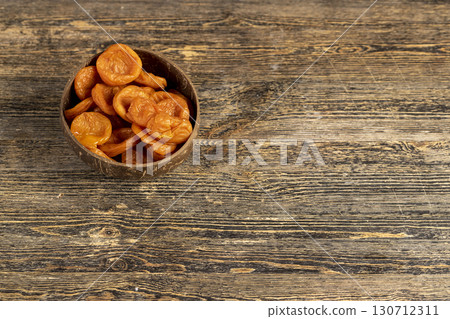 orange dried apricots made from apricots in a coconut shell plate, dried apricots in a bowl made from natural materials 130712311