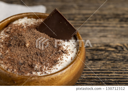 sweet yogurt in a wooden bowl with chocolate crumbs, chocolate in milk yogurt, sweet dessert with chocolate flavor 130712312