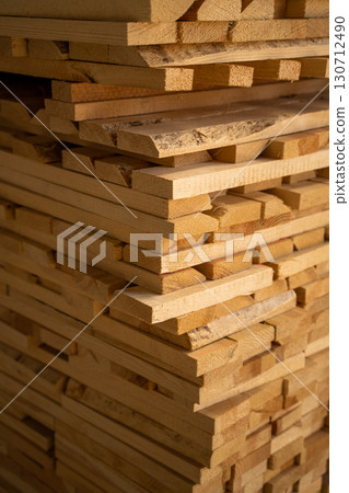 Pile of stacked wooden planks forming a cube shape, rough cut lumber prepared for drying, construction and woodworking applications Pile of stacked wooden planks forming a cube shape, rough cut lumber prepared for drying, construction and woodworking applications 130712490