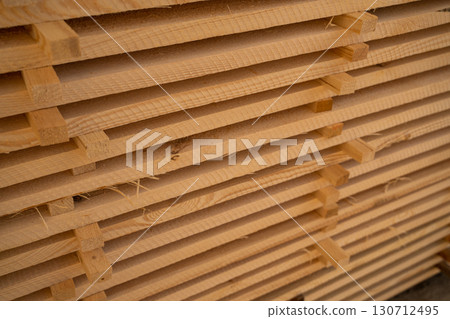 Pile of stacked wooden planks forming a cube shape, rough cut lumber prepared for drying, construction and woodworking applications Pile of stacked wooden planks forming a cube shape, rough cut lumber prepared for drying, construction and woodworking applications 130712495