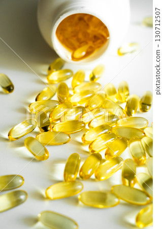 Golden yellow softgel capsules scattered on white background, dietary supplement with vitamins or fish oil in medical concept Golden yellow softgel capsules scattered on white background, dietary supplement with vitamins or fish oil in medical concept 130712507