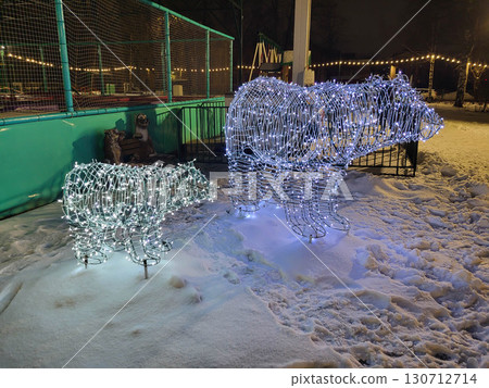 In the winter park, there are two glowing bears made of blue lights. 130712714
