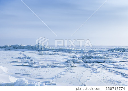 Expansive icy seascape featuring frozen waves, snow-covered terrain Expansive icy seascape featuring frozen waves, snow-covered terrain 130712774