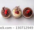 Three beautifully crafted chocolate desserts showcase layers of rich flavors. Each dessert features unique toppings like raspberries, chocolate curls, and cherries, inviting a sweet experience. 130712949