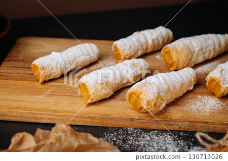 Caramel cream filled pastry rolls dusted with powdered sugar on parchment paper Caramel cream filled pastry rolls dusted with powdered sugar on parchment paper 130713026