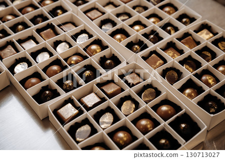 Luxury artisan chocolate bonbons with golden finish in elegant white gift boxes Luxury artisan chocolate bonbons with golden finish in elegant white gift boxes 130713027