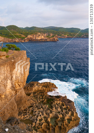 Cinematic aerial landscape shots of the beautiful island of Nusa Penida. Huge cliffs by the shoreline and hidden dream beaches with clear water and foaming wave. 130713339