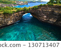 Rock broken by an ocean wave forming an arch in the mountain. Cliff is washed by powerful waves of ocean. Angel's Billabong is a popular tourist destination on the island of Nusa Penida in Indonesia. 130713407