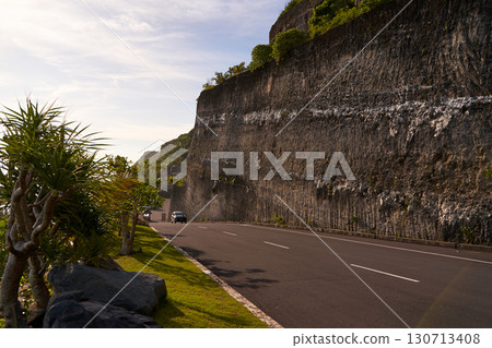 The cliff overhangs along the road to the ocean at sunset. 130713408
