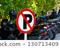 Warning sign - parking is prohibited. Full motorcycle parking near a no parking sign. 130713409