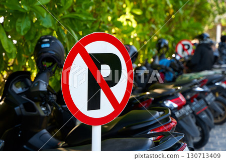 Warning sign - parking is prohibited. Full motorcycle parking near a no parking sign. Warning sign - parking is prohibited. Full motorcycle parking near a no parking sign. 130713409
