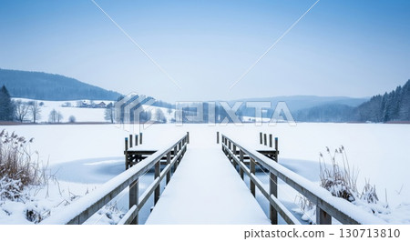 Wooden Dock Covered in Snow on a Frozen Lake Surrounded by Snowy Evergreen Trees 130713810