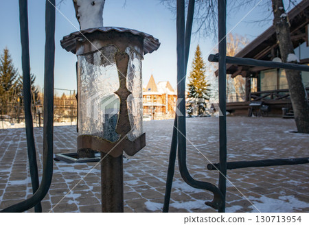 Wrought iron outdoor lantern with crackle glass, winter chalet and blue sky Wrought iron outdoor lantern with crackle glass, winter chalet and blue sky 130713954