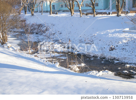 Urban creek in winter with snow and ice, shadows on the park bank Urban creek in winter with snow and ice, shadows on the park bank 130713958