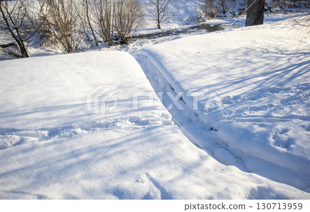 Snowdrifts with trench and long shadows, winter background with copy space Snowdrifts with trench and long shadows, winter background with copy space 130713959